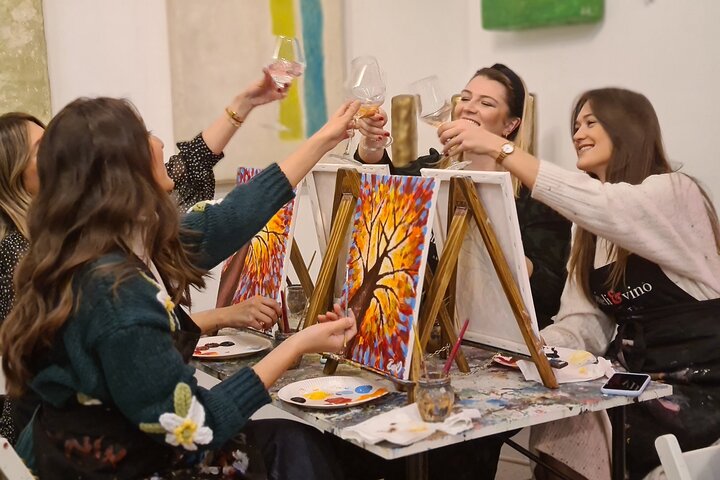Women enjoying painting class with drinks in a cozy art studio setting